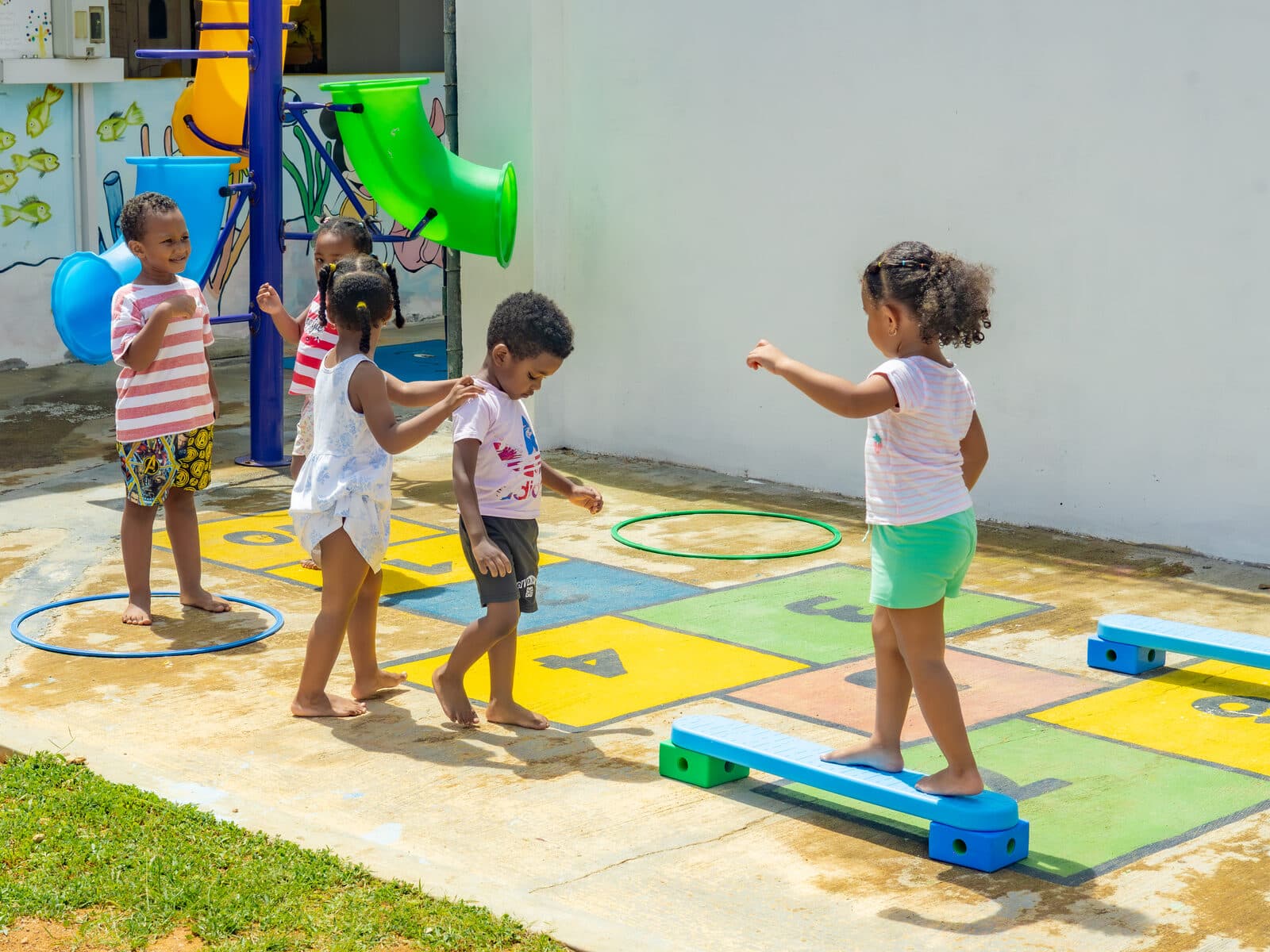 Children playing on a colourful balance beam and hopscotch course outdoors